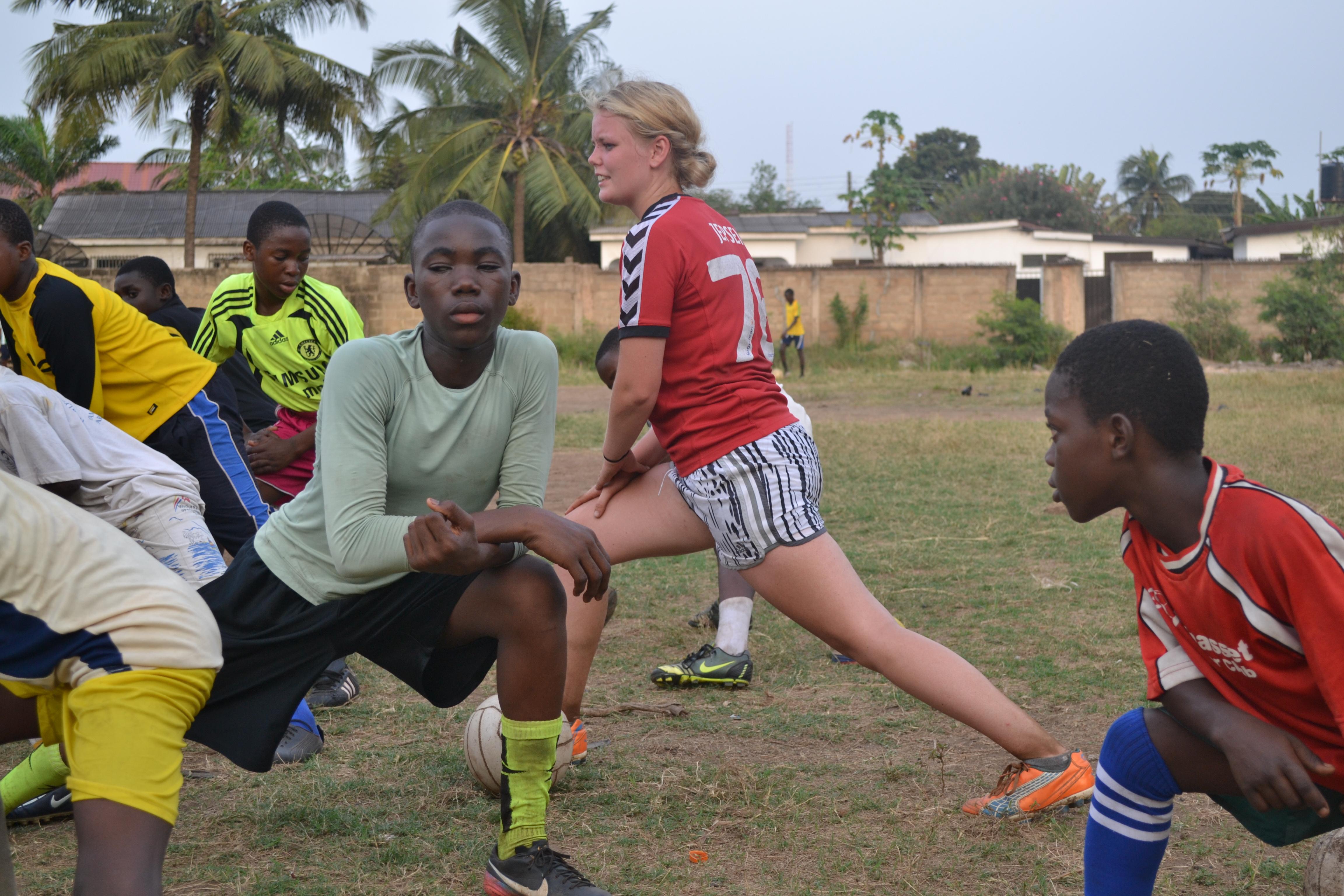 A volunteer football coach in Ghana does stretches with a sports team A Projects Abroad volunteer warms up before teaching football in Ghana